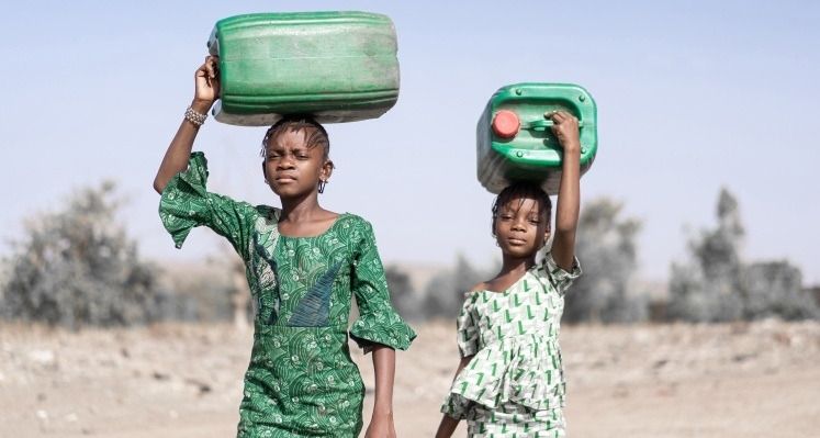Girls carrying water cans